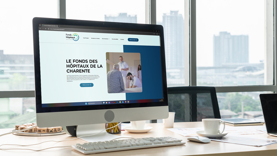 Mock-up du site de Fonds des Hôpitaux de la Charente. La page d'accueil du site est ouverte sur un ordinateur posé sur un bureau.